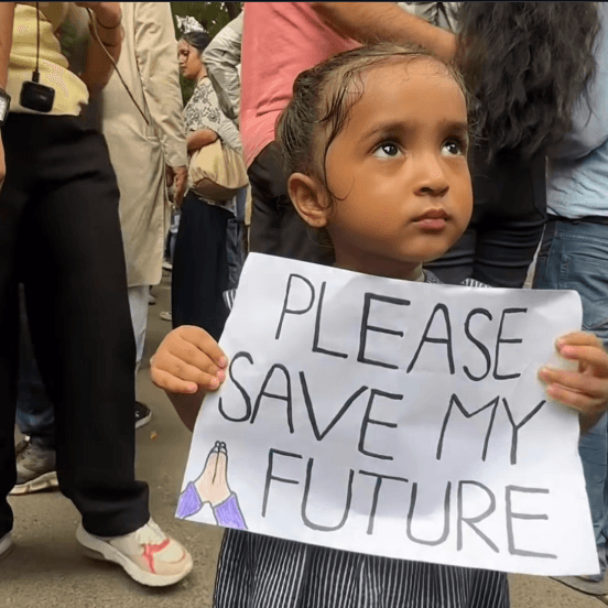 A child at the protest holds a placard reading: Please save my future